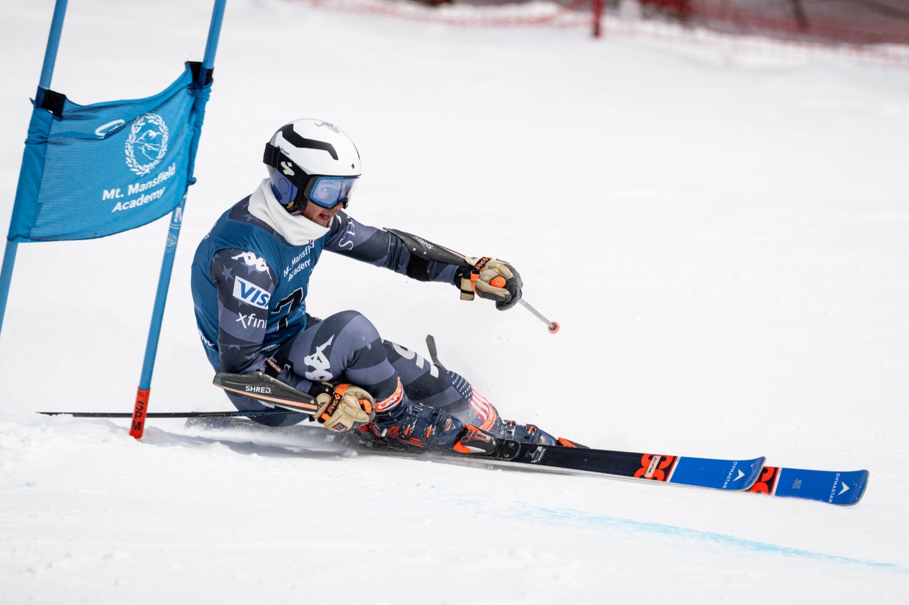 Vivaan Alleyne on a giant slalom turn, low over the inside ski, passing a blue gate
